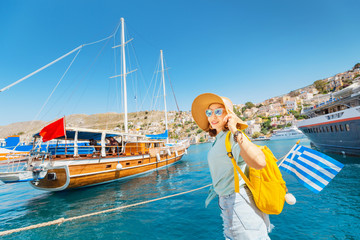 Happy woman with greek flag near cruise ship. Sea vacation and travel concept
