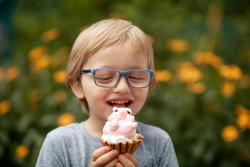 a happy child, a boy of 4-5 years old, is eating a delicious cake in the form of a pig