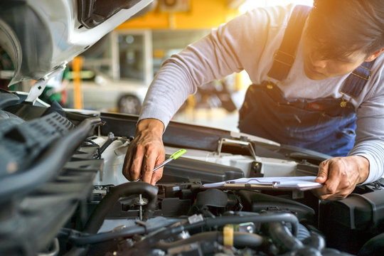 Professional mechanic holding a clipboard of service and check engine in garage. Repair service.