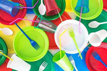 Bright color disposable plastic tableware  background. Picnic set. Ecology problem. Top view.	