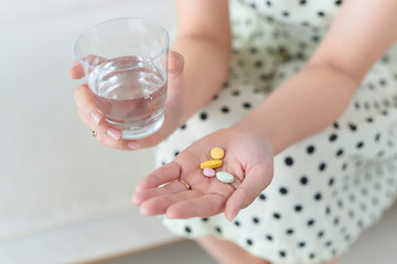 Woman with pills and glass of water indoors