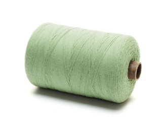 Green spool of thread in a horizontal position on a white background