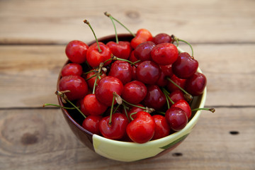ripe red sweet cherry in a bowl on a wooden table