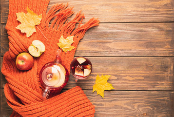 Drink autumn apple red berries in a glass teapot and an orange scarf on a wooden background. Hot...