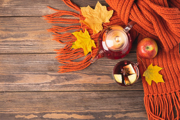 Drink autumn apple red berries in a glass teapot and an orange scarf on a wooden background. Hot...