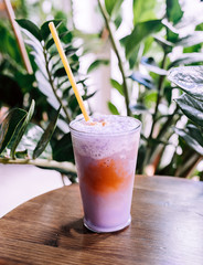 summer drink: pink frappe coffee, smoothie or milkshake with tropical plants on the background