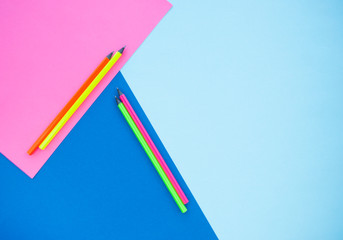 Colorful paper, neon pencils on blue and pink background. Flat lay style. Back to school concept.