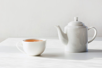 Time for tea. Set of cup and teapot on white. Minimal composition.