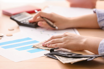 Young woman counting income at table, closeup