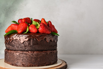 Tasty chocolate cake with strawberry on table against light background