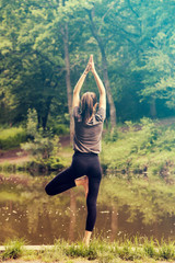 Beautiful woman meditating by the water