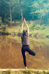 Beautiful woman meditating by the water