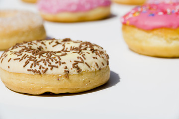 Delicious donuts with sprinkles on white backdrop