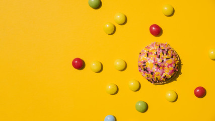 Candies with sprinkle donut on yellow background