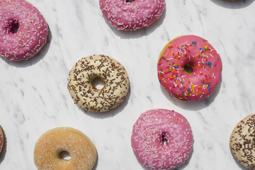 An overhead view of colorful donuts on marble textured backdrop