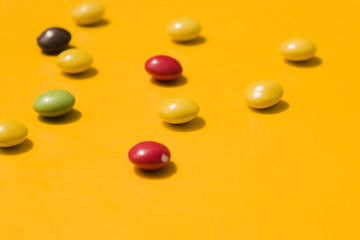 Colorful candies on yellow backdrop