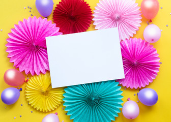 Holiday frame or background with colorful balloon, gift, confetti, paper flowers on yellow background. Flat lay style. Birthday or party greeting card with copy space.
