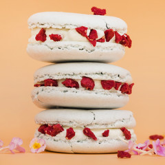 Stacked of macaroons with flowers against pink colored background