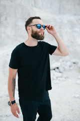 Handsome hipster man with beard wearing black blank t-shirt with space for your logo or design.