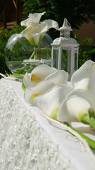White decoration table for celebrations - White lantern and calla lily in a round glass vase