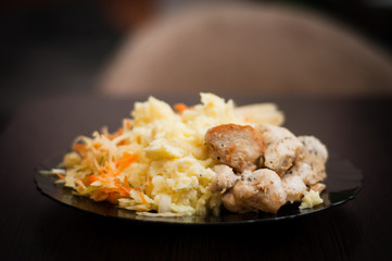 Traditional homemade lunch for a good muscle recovery athletes. Fried chicken meat with boiled potatoes and vegetable salad of carrots and cabbage.