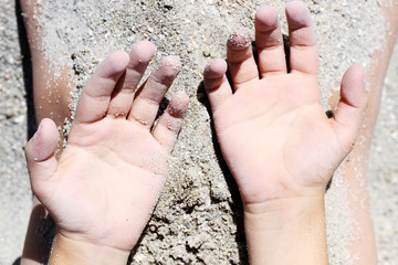 Part of body with sand. Childish hands have a fun in sand.