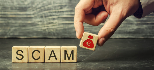 Businessman puts wooden blocks with the word Scam. Fraudulent investment project. Illegal plan to...