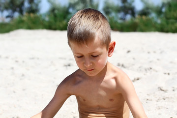 Little boy is playing with sand in summer beach