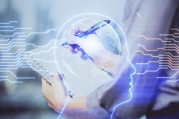 Multi exposure of woman's writing hand on background with brain hologram. Concept of brainstorming.
