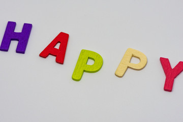 The HAPPY text from colorful wooden letters is on white background, learning alphabet, Sensitive focus.