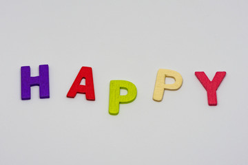 The HAPPY text from colorful wooden letters is on white background, learning alphabet, Sensitive focus.