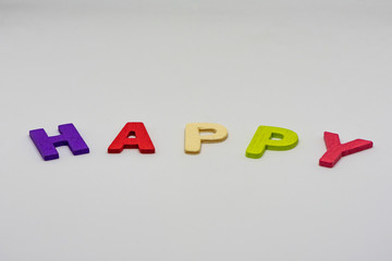 The HAPPY text from colorful wooden letters is on white background, learning alphabet, Sensitive focus.