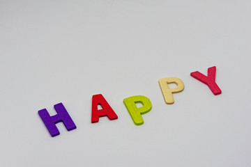 The HAPPY text from colorful wooden letters is on white background, learning alphabet, Sensitive focus.