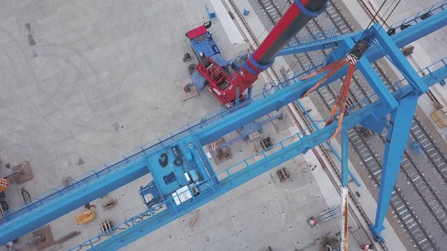 Aerial view of red tower crane standing near the railway in the industrial zone. Clip. Construction and manufacturing processes