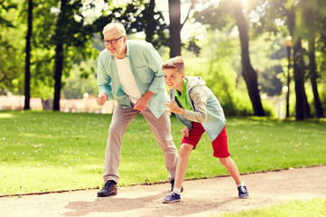 Fototapeta premium family, generation and people concept - happy grandfather and grandson racing at summer park