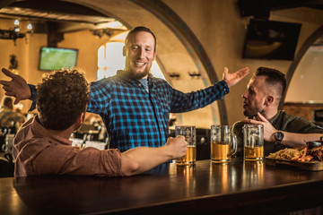 Friends drinking draft beer and watching tv in a pub