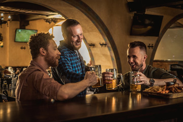 Friends drinking draft beer and watching tv in a pub