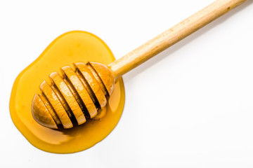 Honey dipper in yellow drop of honey isolated on white background
