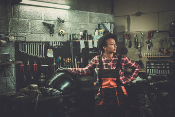 African american woman mechanic repairing a motorcycle in a workshop