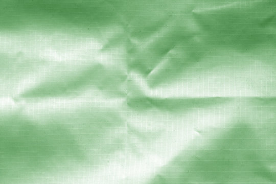 Crumpled transparent plastic surface in green color.