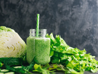 Green diet smoothie for weight loss with cabbage, cucumber, lettuce on the table, copy space