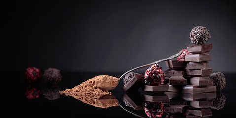 Chocolate candies, broken chocolate pieces and spoon with cocoa powder.