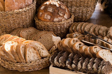 Obraz premium Bread from different types of flour of cereal seeds. Baking in straw baskets on a large wooden table. Rustic style.