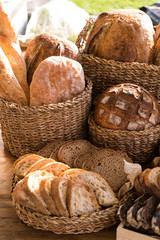 Bread from different types of flour of cereal seeds. Baking in straw baskets on a large wooden table. Rustic style.