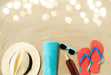 vacation, travel and summer holidays concept - straw hat, flip flops, sunglasses and sunscreen oil with seashells on beach sand