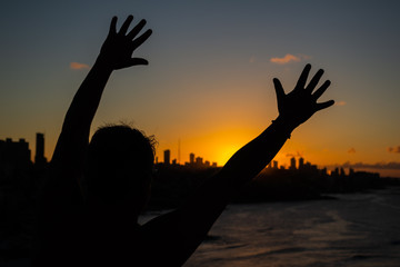 Man facing the sunset sun with his hands outstretched. Sensation of happiness and joy.