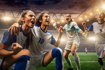 Happy Female Soccer players on a professional soccer stadium. Girls Team emotionally celebrates...