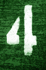 Number 4 in stencil on grungy metal wall in green tone.