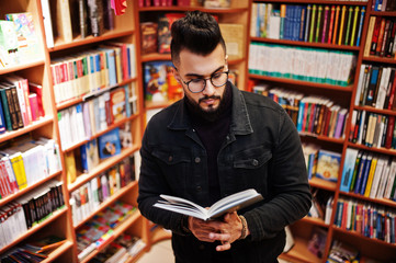 Tall smart arab student man, wear on black jeans jacket and eyeglasses, at library with book at hands.