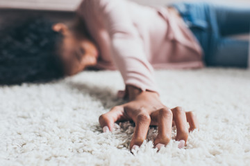 selective focus of african american woman suffering from pain while lying on floor